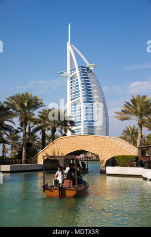 I turisti a cavallo su un abra sulle vie navigabili del Madinat Jumeirah con il Burj Al Arab dietro, Dubai, Emirati Arabi Uniti, Medio Oriente Foto Stock