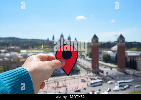 Primo piano della mano di un giovane uomo caucasico con un indicatore rosso nella Plaça de Espanya a Barcellona, Spagna, con le Torri Veneziane e il Palau Nac Foto Stock