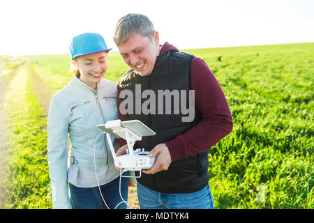 Quadcopter all'aperto, immagini aeree hobby divertente, concetto di ricreazione - divertimento di flying drone e video ridere giovane uomo e donna in estate verde erba fie Foto Stock