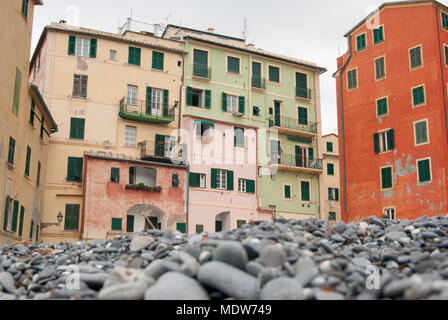 Pietre grigie sulla Spiaggia di Camogli e tipiche case colorate Foto Stock