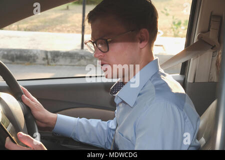 Imprenditore utilizzare app sullo smartphone in auto. uomo caucasico tenendo il telefono cellulare controllo direzione durante la guida Foto Stock