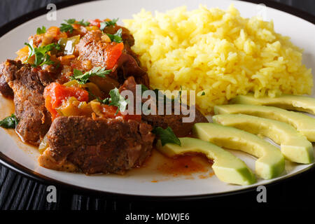 Seco de chivo è stufato di capra con riso giallo e fresche avocado close-up su una piastra orizzontale. Foto Stock