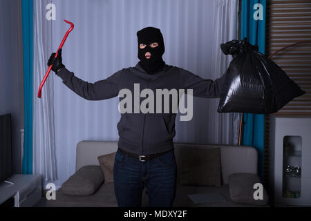 Una chiusura di un rapinatore con maschera di rapina tenendo una torcia  elettrica Foto stock - Alamy