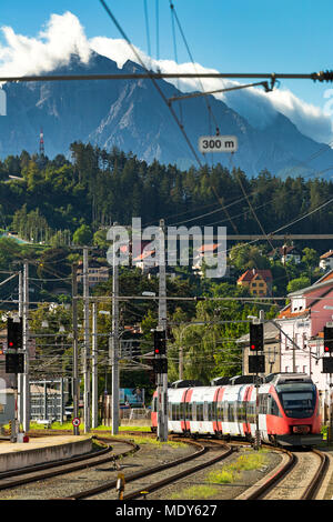 Diesel elettrico treno in avvicinamento della piattaforma con le montagne sullo sfondo e il blu del cielo, Innsbruck, Austria Foto Stock