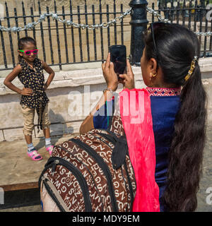 Una madre prende una foto della sua figlia giovane come lei pone alla porta d'India, considerato un 'monumento simbolo' che rappresenta la città di M... Foto Stock