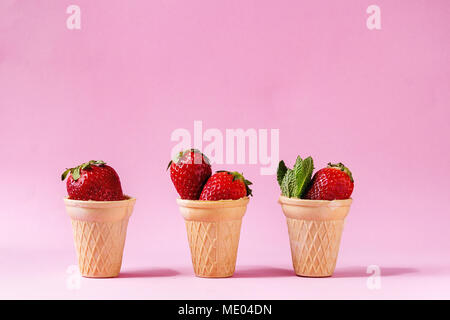 Fragole fresche in tazze waffle su rosa pastello pin-up dello sfondo. Copia dello spazio. Foto Stock