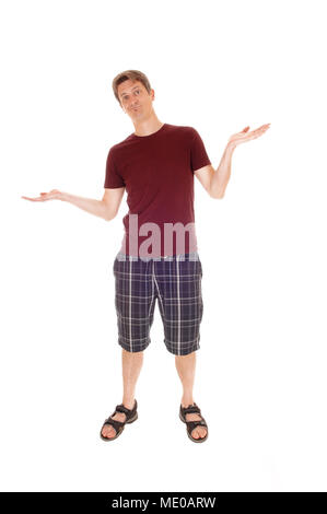 Un giovane uomo in piedi in pantaloncini corti e un borgogna t-shirt con le mani alzate ed è clueless, isolato per sfondo bianco Foto Stock