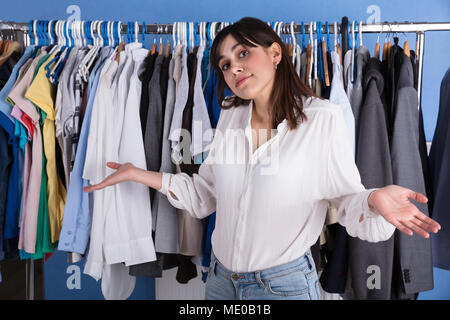 Ritratto di una giovane donna Scrollare nella parte anteriore del bastone appendiabiti Foto Stock