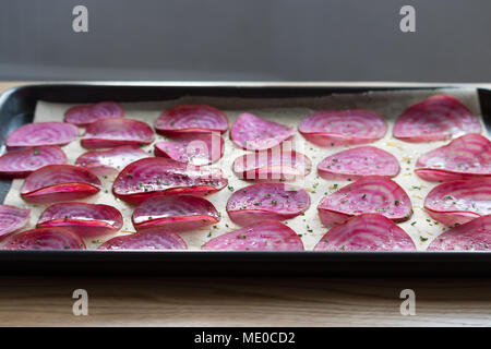 Fette di candy barbabietola chioggia bietole) su un foderata teglia, pronto per preparare e cotte al forno veggie chips. Foto Stock
