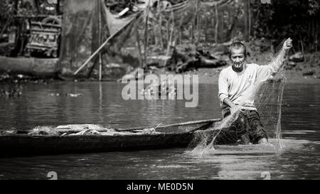 Un uomo di fumare una sigaretta mentre la pesca dalla sua barca sul fiume Mekong, Delta del Mekong; Thoi Un, Can Tho, Vietnam Foto Stock