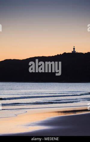 Silhouette di Faro di Cape Byron sulla collina e sulla spiaggia al tramonto a Byron Bay nel Nuovo Galles del Sud, Australia Foto Stock