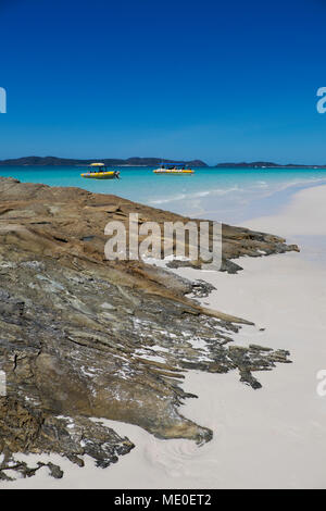 Formazioni di roccia e sabbia bianca sulla Whitehaven Beach con barche ancorate lungo Whitsunday Islands nel Queensland, Australia Foto Stock