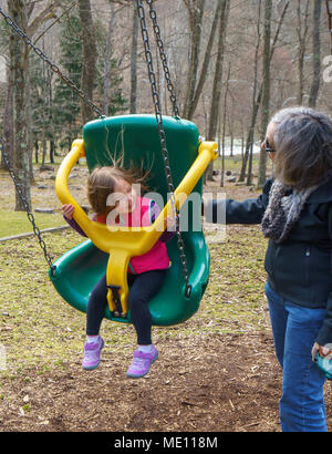 Nonna e nipote giocare in oscillazione in plastica Foto Stock