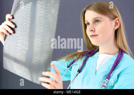Medico donna cerchi a raggi X immagine. Colore uniforme in verde. Viola stetoscopio. Assistenza sanitaria, assicurazione e concetto di medicina Foto Stock