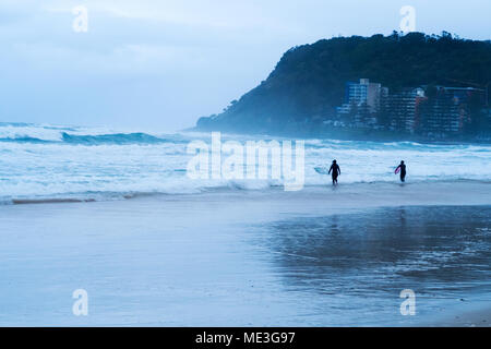 Surfers che entra in mare durante una tempesta di Burleigh capi sulla Gold Coast in Australia Foto Stock