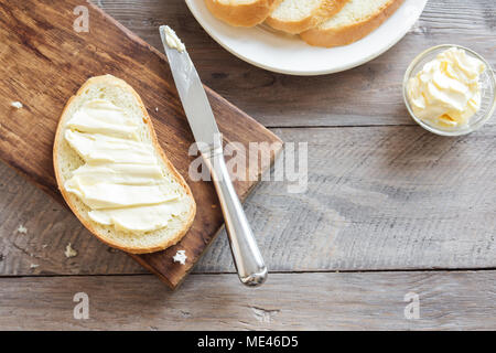 Burro e pane per la colazione su legno rustico sfondo con copia spazio. La colazione del mattino, burro e pane tostato. Foto Stock