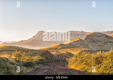 Sunrise sulla strada per la sentinella del parco auto con l'Anfiteatro del Drakensberg nel retro Foto Stock