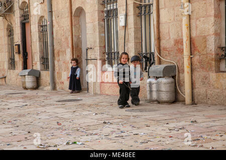 Israele a Gerusalemme il stretto vicolo del popolo ebraico Mea Shearim quartiere, giovani bambini che giocano in strada Foto Stock