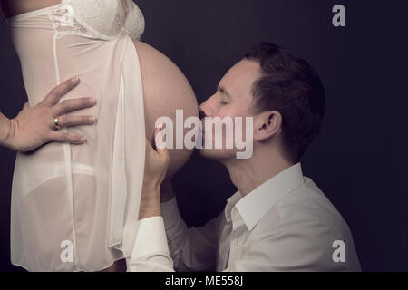 Gestanti padre baci teneramente il ventre in gravidanza di sua moglie Foto Stock