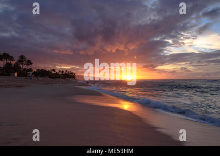 Onde che si infrangono sulla spiaggia come il sole scende come Sunset Beach Park sulla North Shore di Oahu, Hawaii Foto Stock
