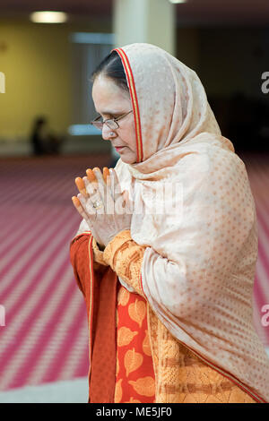 Ritratto di una donna Sikh con orange dita meditando a un matrimonio al Gurdwara Sikh Società culturale nel sud Richmond Hill, Queens, a New York Foto Stock