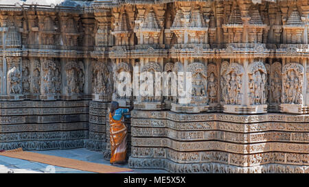 Il Karnataka, India - 2 Marzo 2018: Attendant spazzolatura crepe nelle intricate sculture di pareti del XIII secolo Channakeshava tempio di Somnathpur Foto Stock