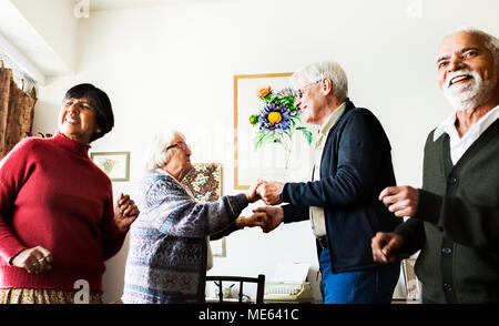 Senior amici ballare insieme a casa Foto Stock