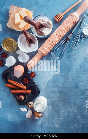 La cottura di ingredienti e utensili da sopra. Scolpiti mattarello, muffin tin, frusta e cucchiai di miele in casa di un concetto di cucina a vista con copia spazio. Foto Stock