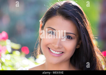 Closeup headshot ritratto di fiducioso sorridendo felice piuttosto giovane donna, isolato di sfondo sfocato alberi, fiori. Umani positivi del viso emozione Foto Stock