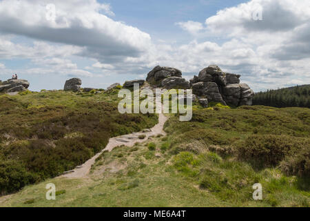 Sentiero stretto che conduce alla cima della collina, grandi rocce s in corrispondenza del picco, sotto una luce blu cielo con spesse nuvole bianche Foto Stock