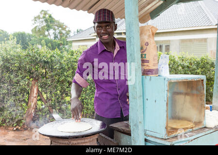 Lugazi, Uganda. 14 maggio 2017. Un giovane uomo una frittura flatbread chiamato 'chapati' in Uganda. Foto Stock