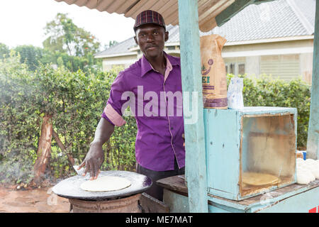 Lugazi, Uganda. 14 maggio 2017. Un giovane uomo una frittura flatbread chiamato 'chapati' in Uganda. Foto Stock