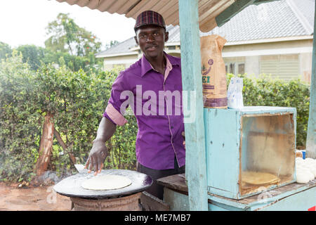 Lugazi, Uganda. 14 maggio 2017. Un giovane uomo una frittura flatbread chiamato 'chapati' in Uganda. Foto Stock