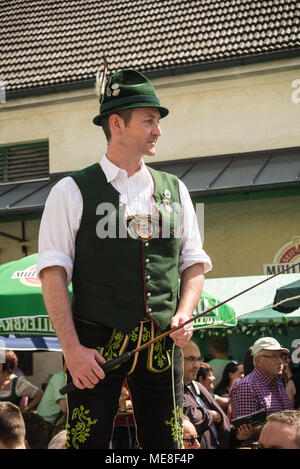 Neuoetting, Germania. 21 aprile 2018, un uomo in tipici abiti bavarese detiene una frusta mentre in piedi su un tavolo Foto Stock