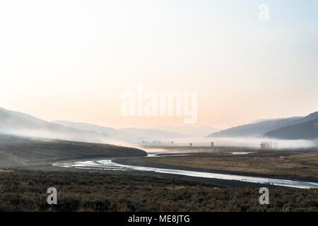 La nebbia e il fumo attraverso il rullo di Lamar valle durante una tarda estate sunrise nel Parco Nazionale di Yellowstone, Wyoming. Foto Stock