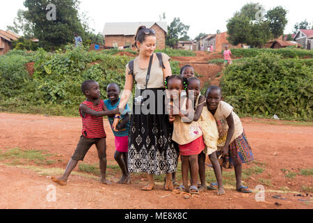 Lugazi, Uganda. 17 maggio 2017. Un bianco-pelato volontario (denominata 'mzungu' o 'muzungu' localmente) tenendo le mani con bambini ugandesi in una zona rurale. Foto Stock