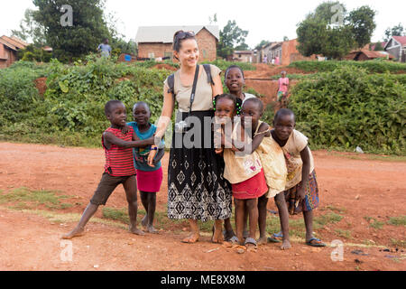 Lugazi, Uganda. 17 maggio 2017. Un bianco-pelato volontario (denominata 'mzungu' o 'muzungu' localmente) tenendo le mani con bambini ugandesi in una zona rurale. Foto Stock