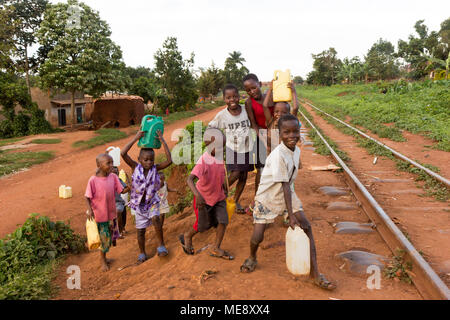 Lugazi, Uganda. 17 maggio 2017. Sorridente bambini ugandesi in esecuzione su un binario ferroviario in una zona rurale in Uganda. Foto Stock