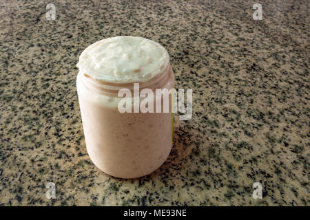 Antipasto sourstay attivo in vaso, pronto all'uso, su fondo di granito. Ricetta: Farina di grano, acqua, lievito fresco - fermentazione biologica Foto Stock