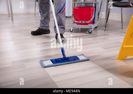 Il detergente per la pulizia del pavimento di legno duro con spazzolone al lavoro Foto Stock