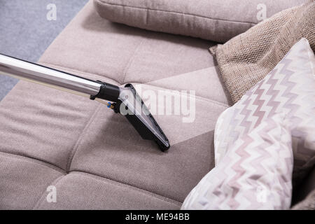 Angolo di Alta Vista di aspirapolvere sul divano sporco a casa Foto Stock