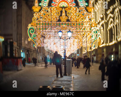 La gente a piedi lungo la strada di notte con una decorazione di luci luminose in inverno a Mosca Foto Stock