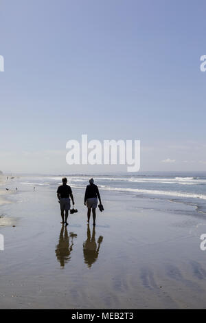 Coppia matura camminando lungo la spiaggia, portando le loro scarpe. Foto Stock