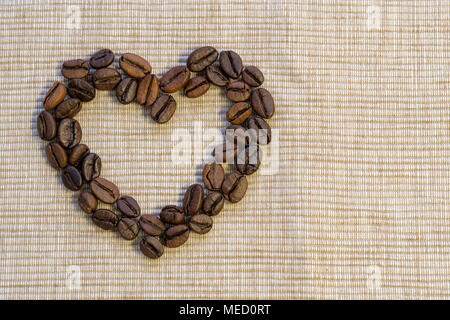 I chicchi di caffè sono enunciate nella forma di un cuore su un tovagliolo beige. Un simbolo dell'amore. Foto Stock