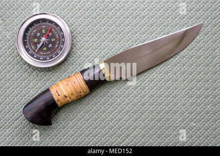 Un coltello da caccia e una bussola giacciono su un tappeto turistica. Attrezzature per il viaggio. Foto Stock