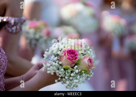 La sposa e le sue damigelle hanno in abiti rosa tenendo il loro bouquet. Foto Stock