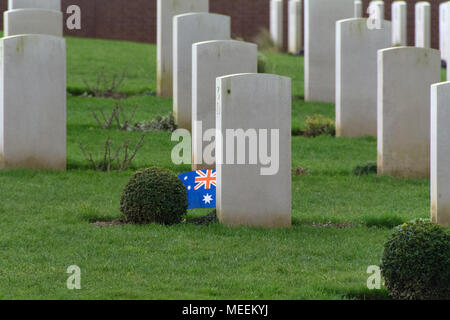 Australian War Graves sul fronte occidentale con una piccola bandiera australiana nel centro del telaio accanto a una delle Lapidi su un rigoglioso tappeto verde di Prato Foto Stock