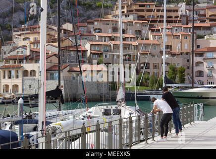 DUINO AURISINA, Italia - 14 Aprile 2018: due ragazzi appoggiati contro una ringhiera presso la marina in Portopicclo, vicino a Trieste, Italia Foto Stock