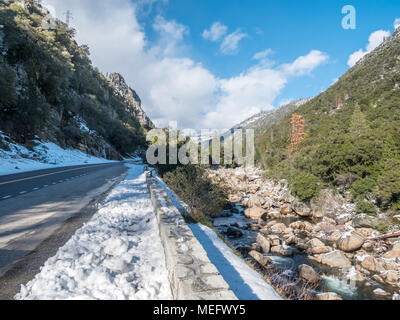 Vista della strada che conduce al Parco Nazionale di Yosemite Park dopo la tempesta di neve con il fiume sulla destra Foto Stock