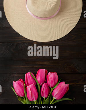 Donna Accessori - hat e bouquet di tulipani rosa su uno sfondo di legno. Messa a fuoco selettiva. Foto Stock